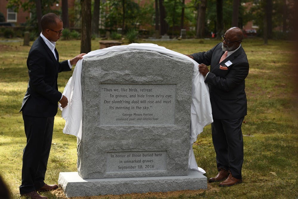 President of the Black Student Movement, Tre Shockley, and Revered Robert Campbell (right) unveil the new marker which honors those buried in unmarked graves in the Old Chapel Hill Cemetery. 