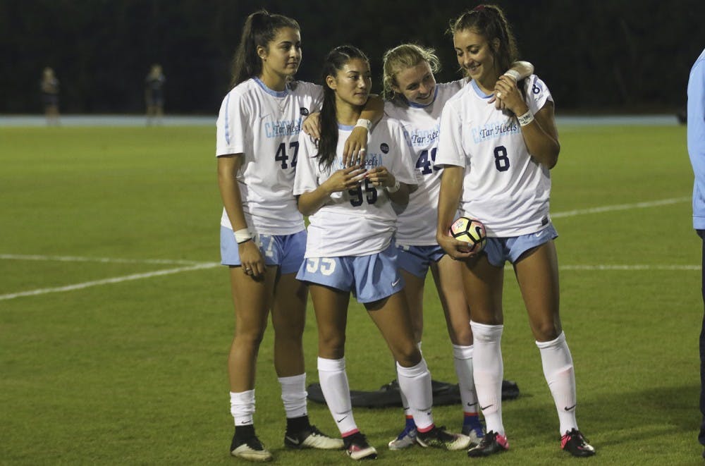 UNC midfielder Abby Elinsky (8) is embraced by her teammates Alex Kimball (47), Jenny Chiu (95) and Cannon Clough (49) before the start of Thursday night's game against Florida State. Elinsky lost her older brother, Nick, on October 2nd.