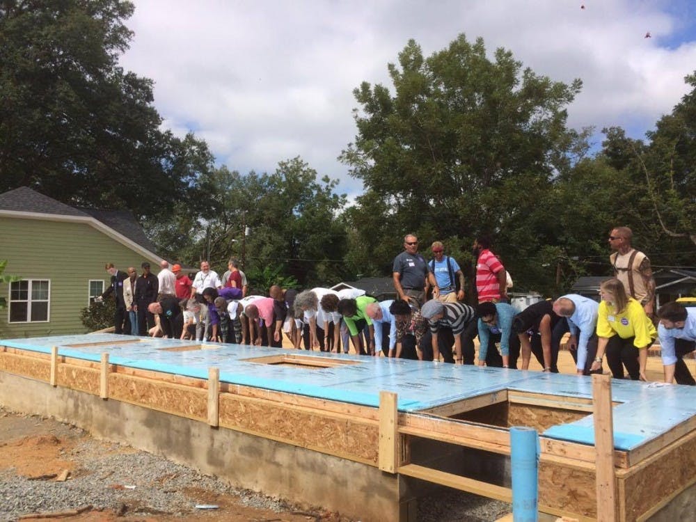 <p>Community members gather to raise a wall to commemorate the accomplishments made during the first year of the Northside Neighborhood Initiative. Photo courtesy of Sally Bitar.&nbsp;</p>
