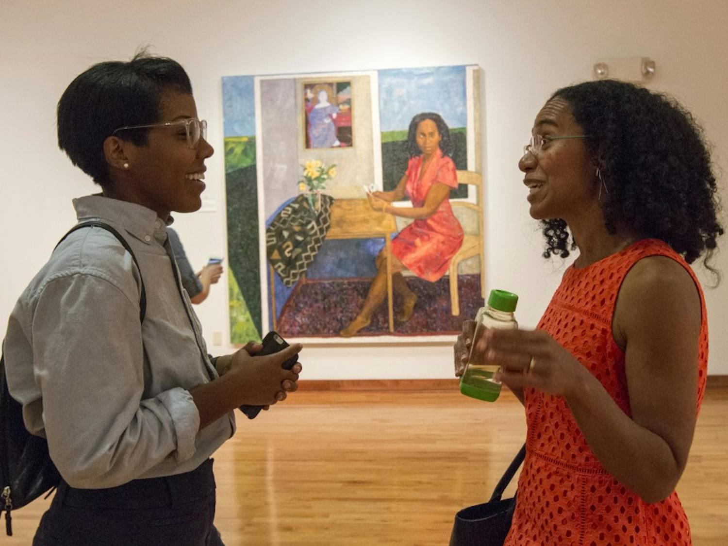 Christina Perkins (left) talks with artist Mequitta Ahuja (right) about her artwork during her exhibit, Meaningful Fiction and the Figurative Tradition, in the Sonja Haynes Stone Center for Black Culture and History on Thursday evening.&nbsp;