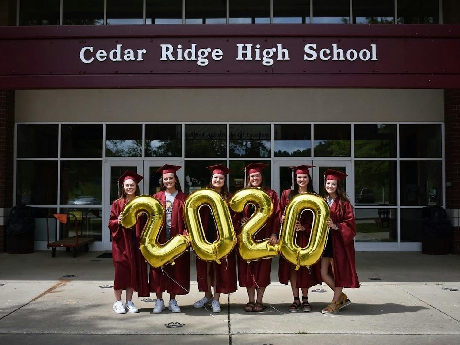 Cedar Ridge Class of 2020 graduates stand in front of Cedar Ridge High School on Friday, May 15, 2020. In lieu of an in-person graduation, the school has proposed a "drive-thru" graduation ceremony, a solution that many students are opposed to. Photo courtesy of Caitlyn Loyd and photographer Shili Quade