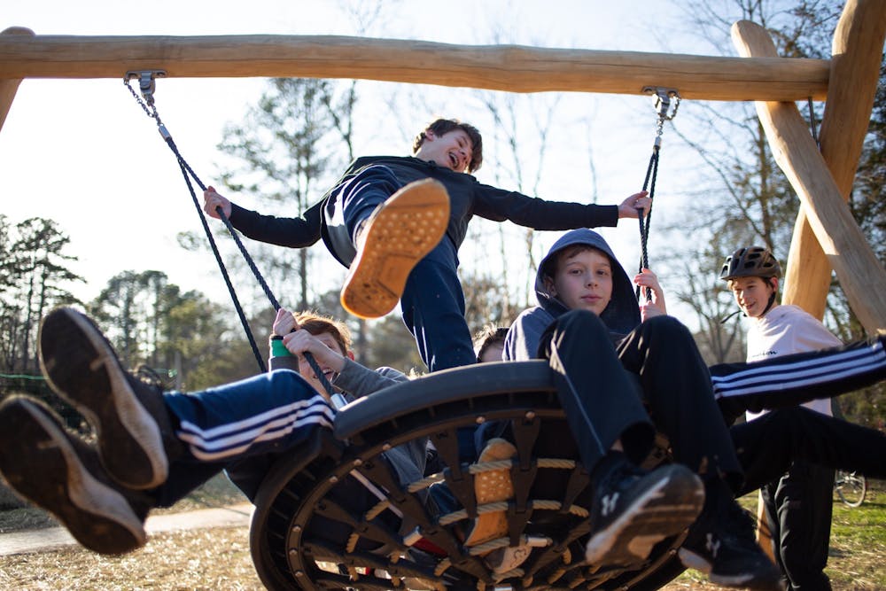 <p>(From left) Josh Delaney, 12, Ben Dover, 13, and Connor Pants, 10, swing as Dexter McQueen, 12, looks on at the recently opened Martin Luther King Jr. Park on Monday, Jan. 20, 2020. Members of the community gathered for the park's ribbon-cutting two years after the initial groundbreaking.</p>