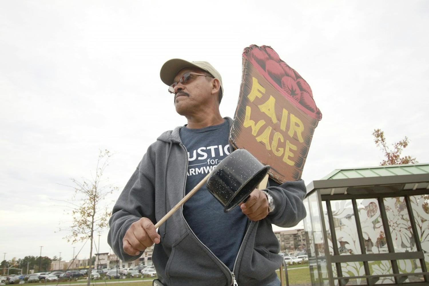 CIW farmer Santiago Perez holds signs in protest at the Cary Publix. The workers are fighting for fairer wages and produce prices.