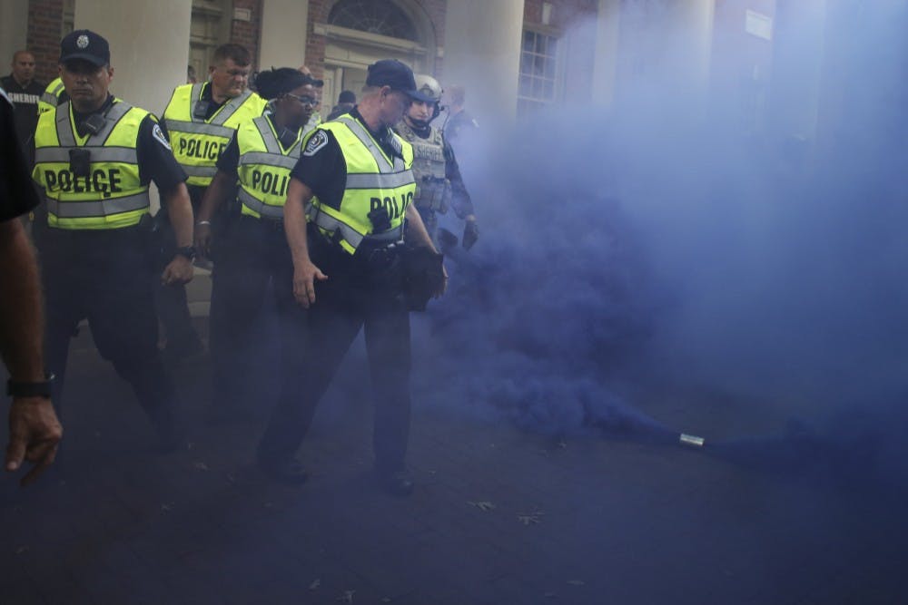 <p>A smoke grenade deployed by the police to disperse the angry crowd of counter demonstrators fills the air with blue smoke on Saturday, September 8th.</p>