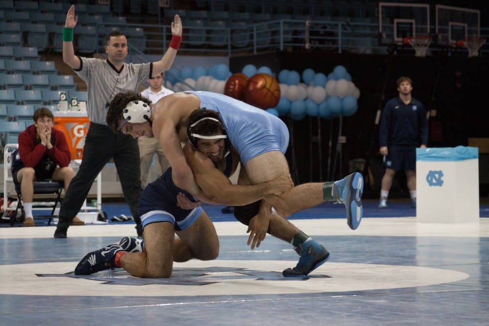 <p>Redshirt senior Ethan Ramos (in Navy) goes for the legs of sophomore teammate Devin Kane during UNC's wrestle-offs on Friday night in Carmichael Arena. &nbsp;</p>