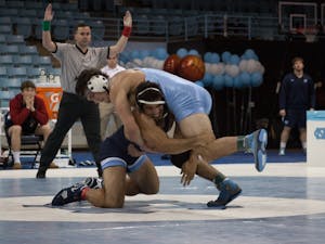 Redshirt senior Ethan Ramos (in Navy) goes for the legs of sophomore teammate Devin Kane during UNC's wrestle-offs on Friday night in Carmichael Arena. &nbsp;