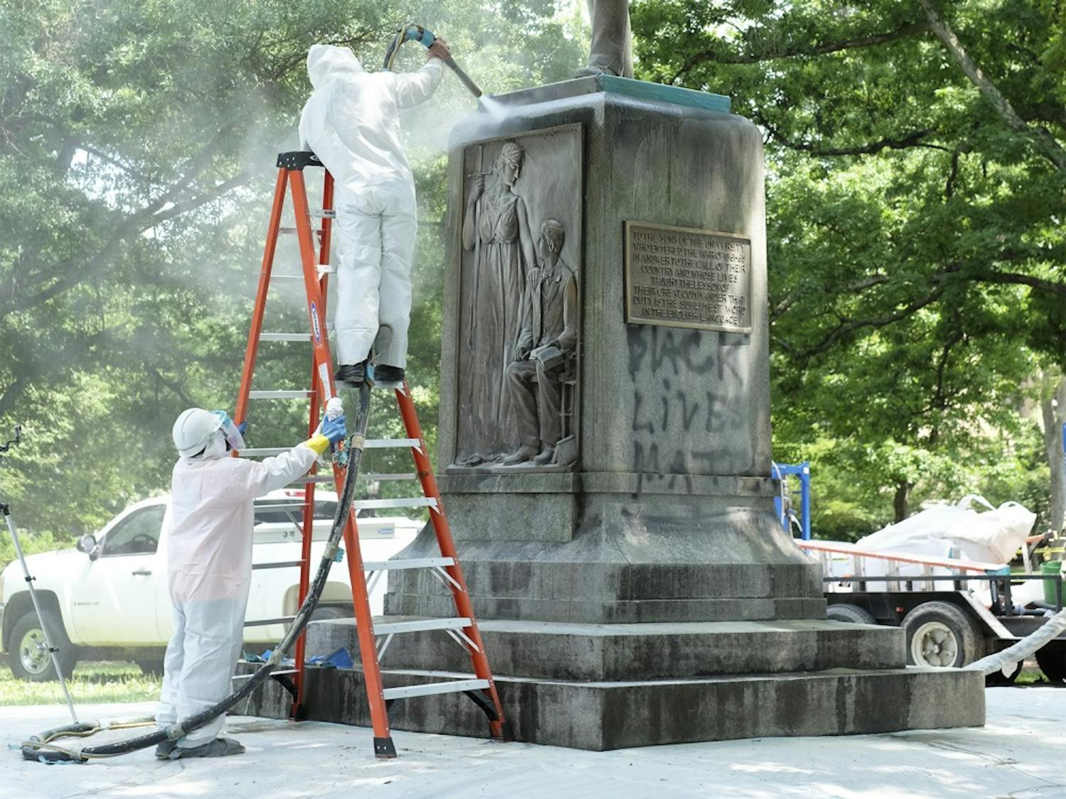 Workers remove graffiti from the Silent Sam monument on Tuesday.