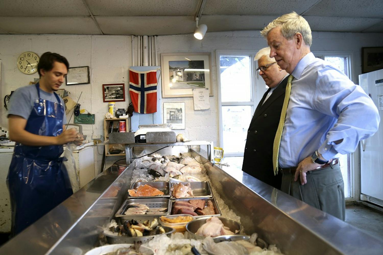 (From left) Sam Sockwell, a worker for Tom Robinson’s Sea Food, works behind the counter for Mark Pandick and Larry Logan.