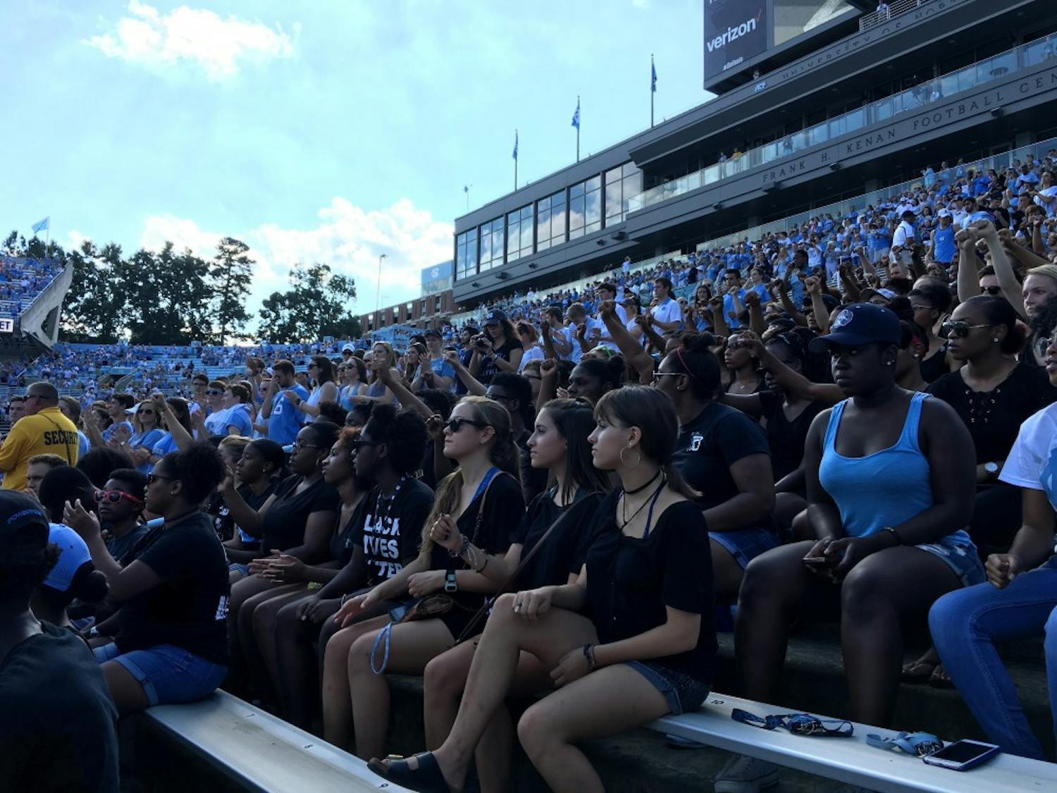 While "The Star-Spangled Banner" played in Kenan Stadium Saturday, protestors remained seated and raised their fists.