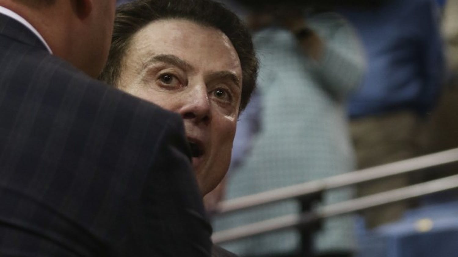 Louisville head coach Rick Pitino is held back by his assisant coaches after reacting to a North Carolina fan shouting "you suck, Rick" as the coach was walking into the locker room at halftime.