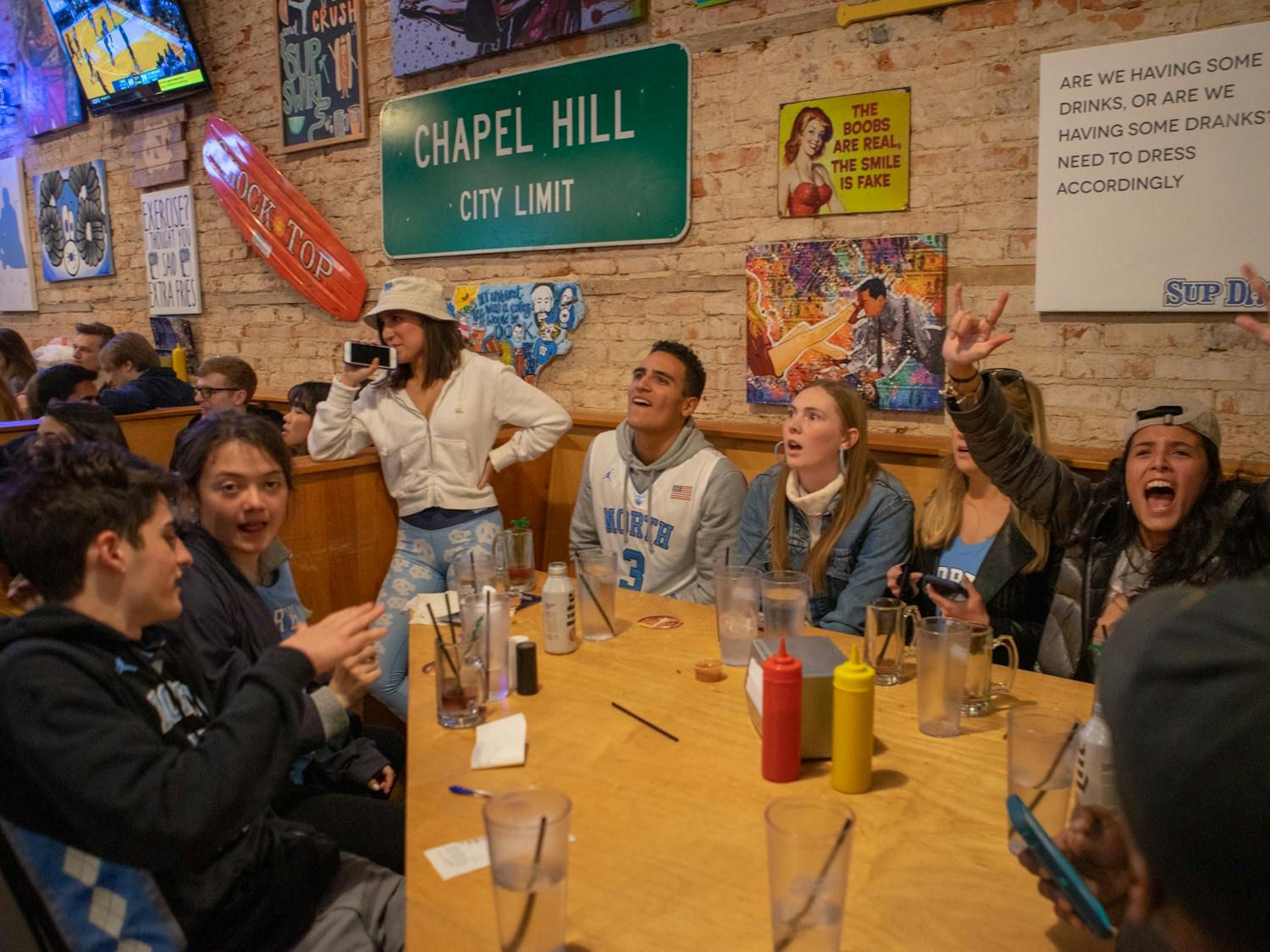 Spectators in Sup Dogs on Franklin Street cheer during UNC's game against Duke following the Tar Heels taking a 10-point lead on Sat. 8, 2020.  The Tar Heels lost to Duke 98-96 in overtime.