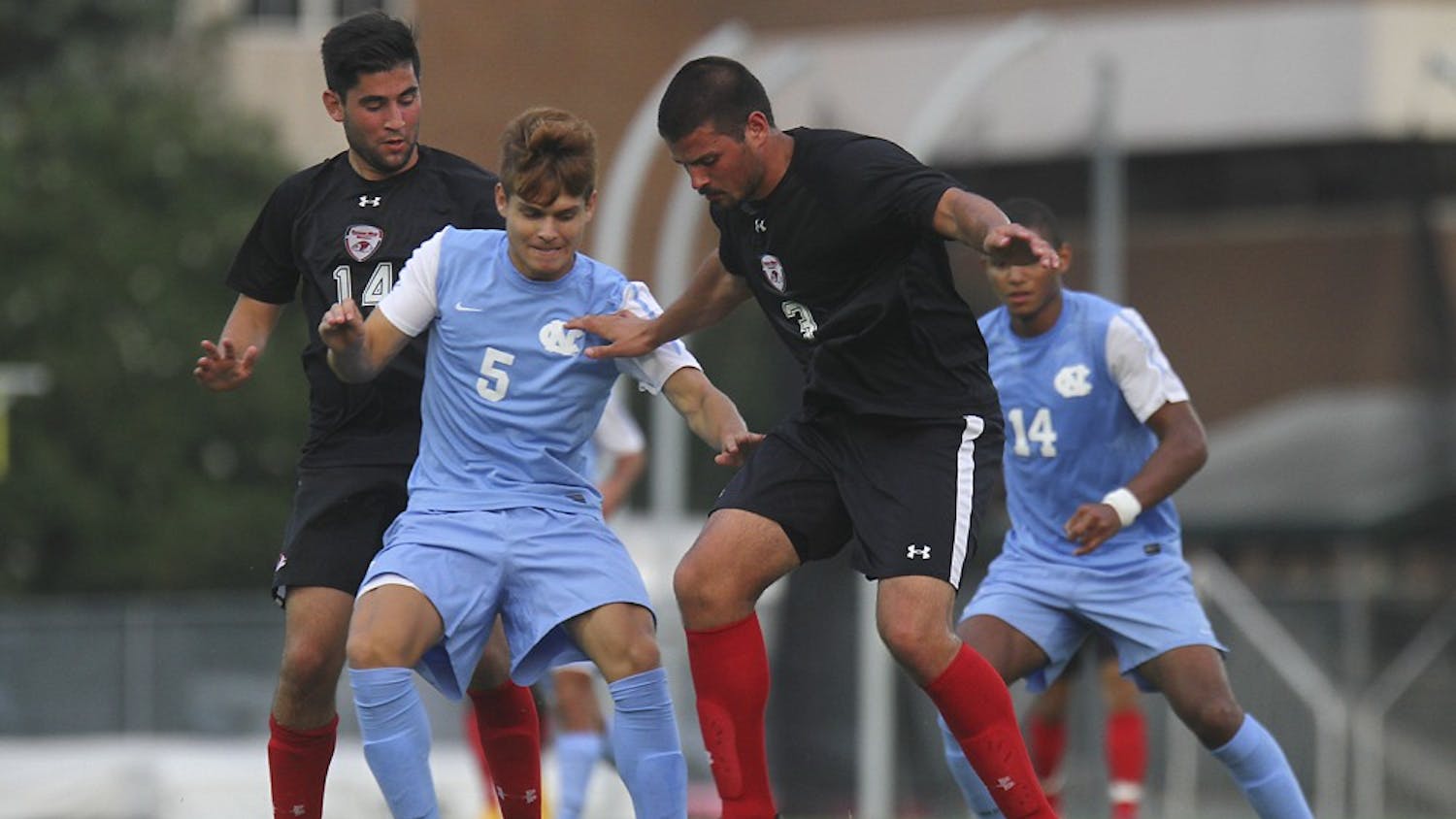 UNC forward, Alan Winn (5), makes a play on the ball against Gardner-Webb defender Matt Bogart (3) and mid-fielder Patrick Gurser (14).  Winn would finish the match with a goal early in the second half.  UNC defeated Gardner-Webb 7-0 Friday night at Fetzer field in an exhibition game.