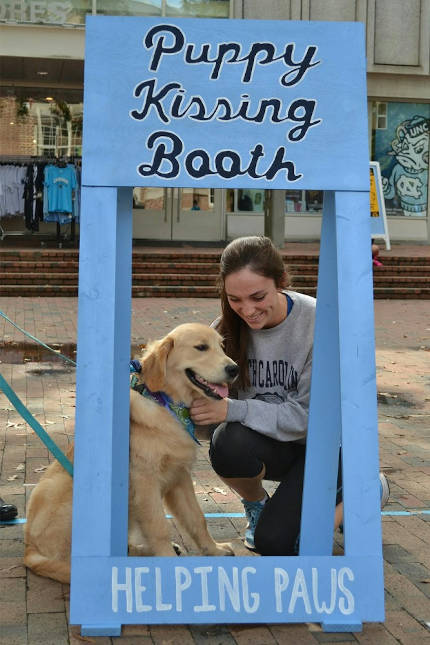 UNC junior Kirsten Wiedbusch shares a moment with Holden the Golden Retriever at the Helping Paws Puppy Kissing Booth.
