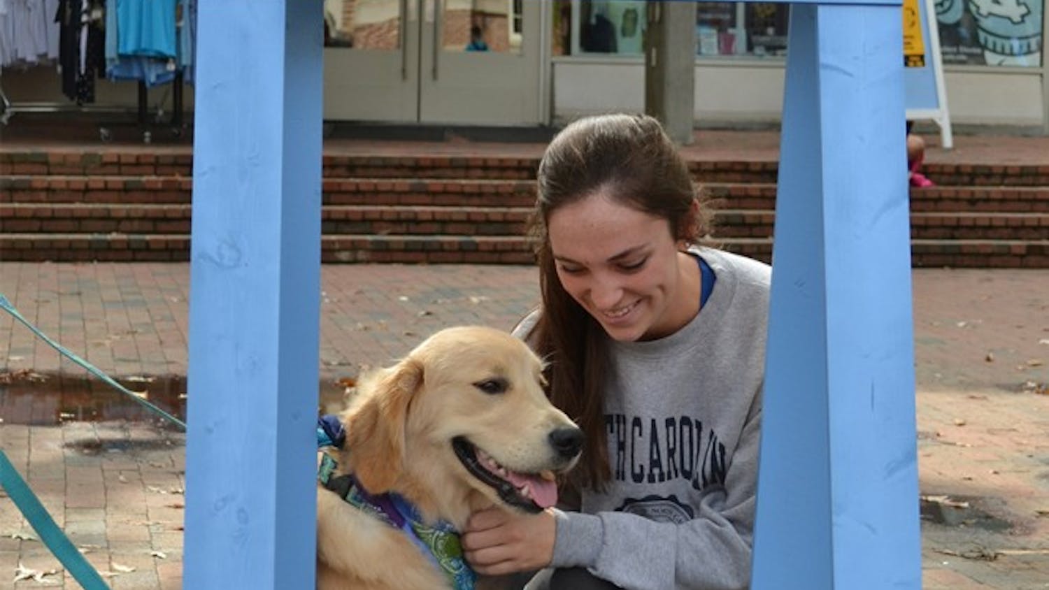 UNC junior Kirsten Wiedbusch shares a moment with Holden the Golden Retriever at the Helping Paws Puppy Kissing Booth.