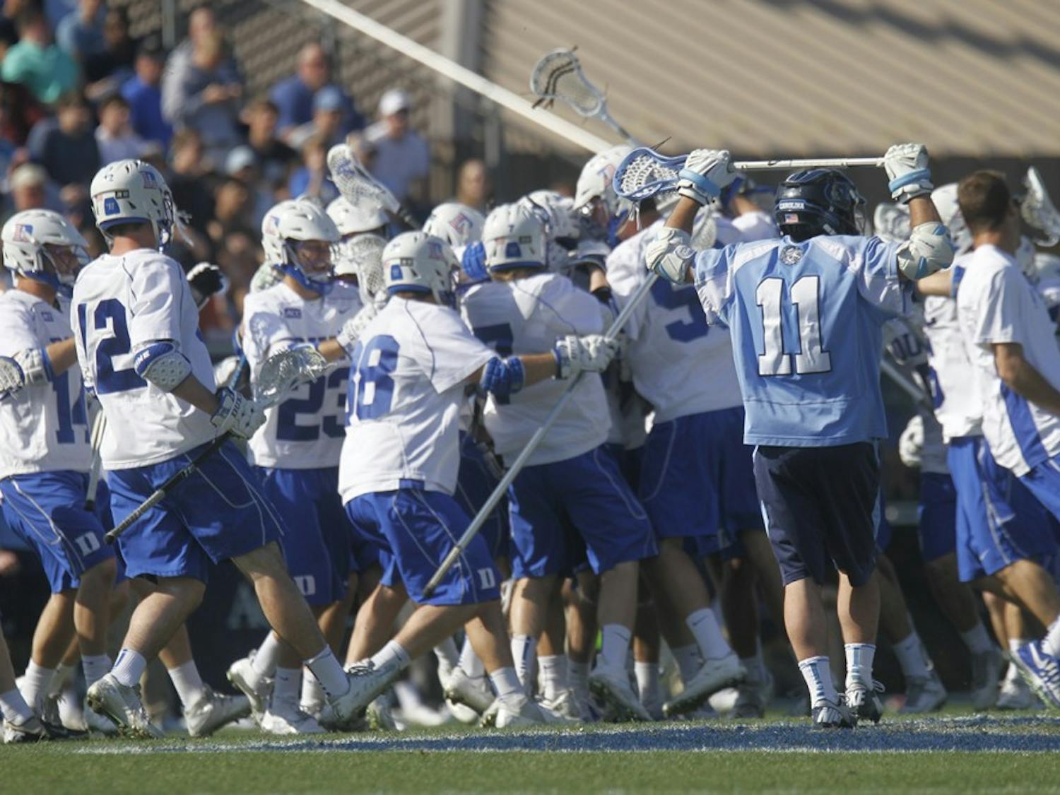 	Joey Sankey (11) puts his hands up as the Duke lacrosse team celebrates after Duke’s Jordan Wolf scored in overtime to win the game 9-8. 