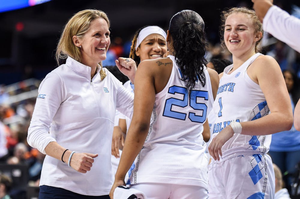 <p>UNC women's basketball head coach Courtney Banghart offers junior guard Deja Kelly (25) a fist bump during the team's second-round matchup against Clemson in the 2023 ACC Tournament in Greensboro, N.C. UNC won 68-58.</p>