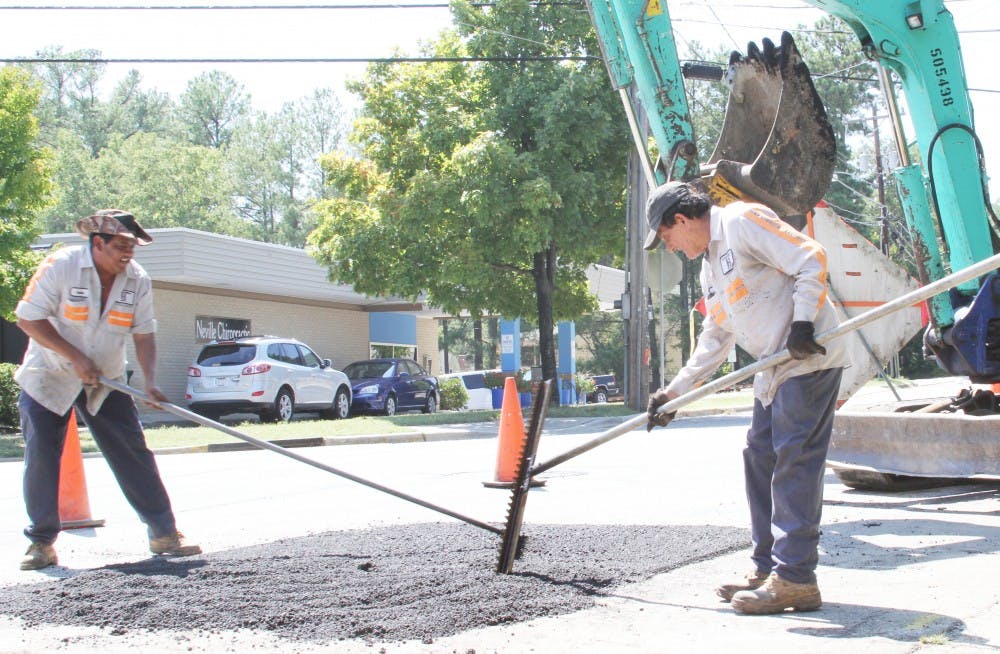 Workers Susano Soto (left), Emilio Hernadez (center), and Lee Johnson (right) of Raleigh's Blalock Paving company repair a road in Carrboro near Jones Ferry Road.  The company hires many of the day laborers who gather in the area to be picked up for jobs. 