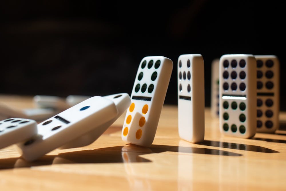 A DTH Photo Illustration. A row of dominoes falls over one by one.