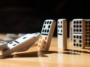 A DTH Photo Illustration. A row of dominoes falls over one by one.