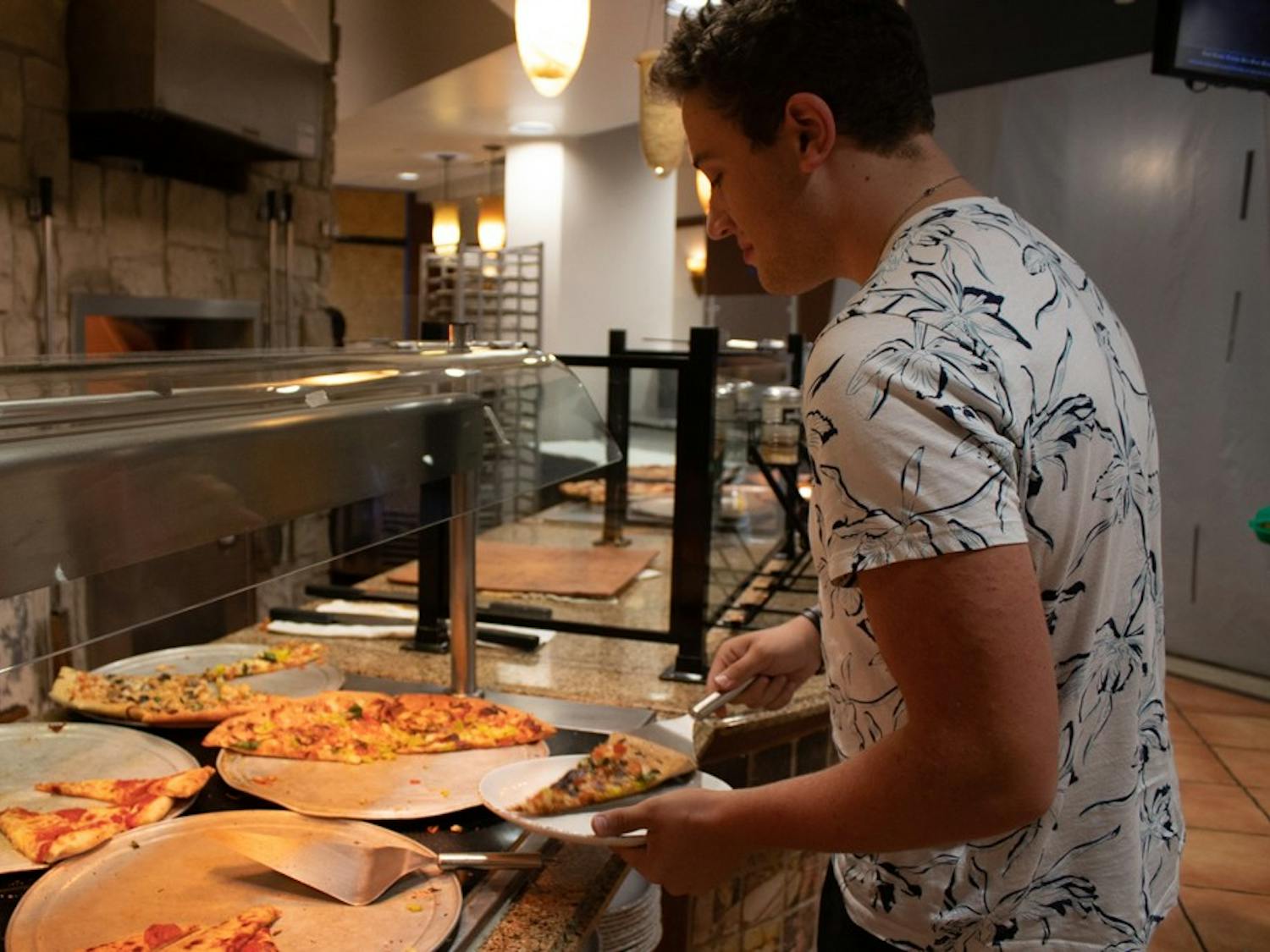 Maxfield Palmer, a first-year biology major, grabs a slice of pizza from Chase Dining Hall on Tuesday, Oct. 1, 2019.
