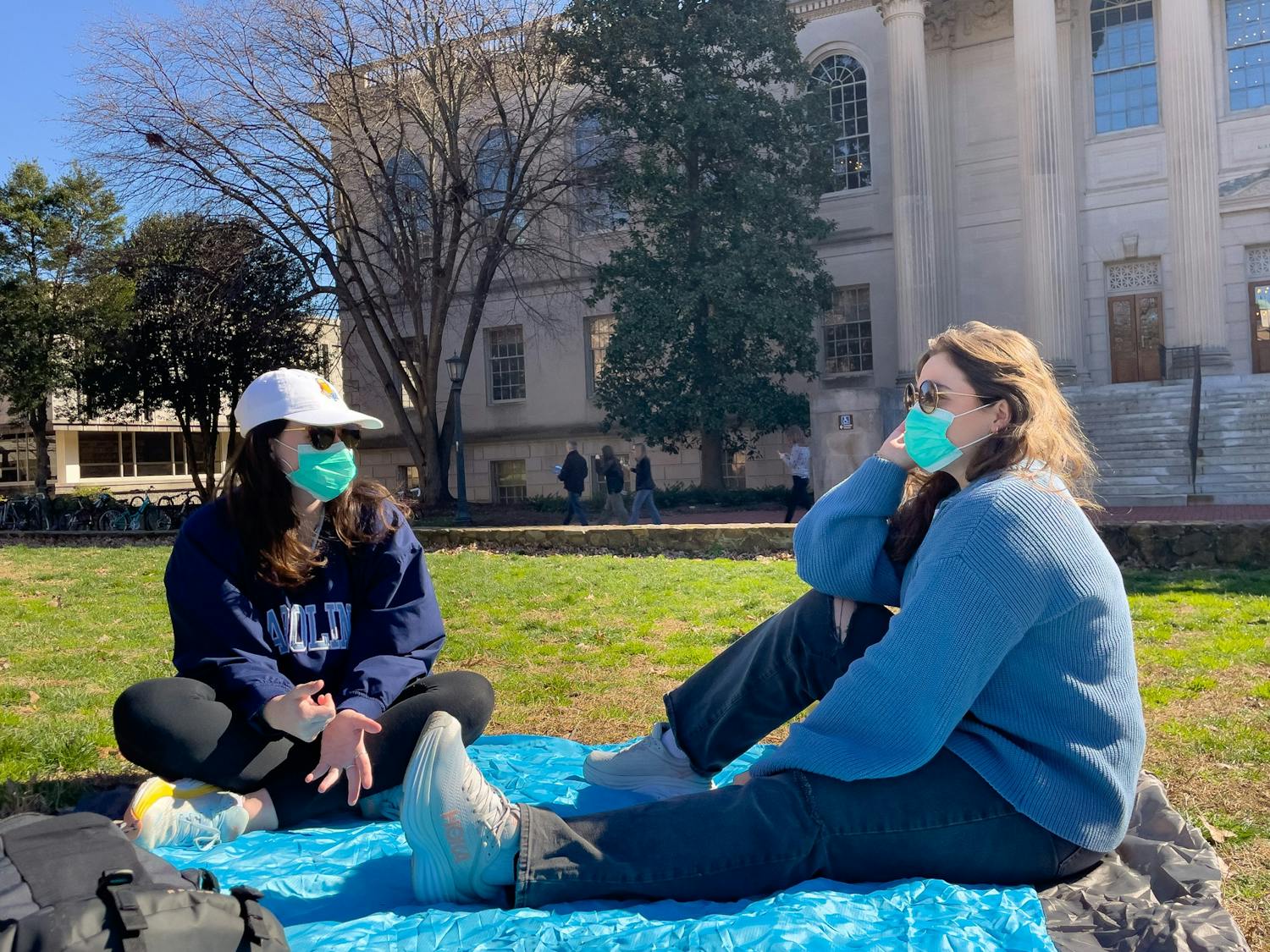 UNC-CH sophomores Sydney Martin and Megan O'Connor wear masks and hang out in the quad in front of Wilson Library on Feb. 6, 2023.