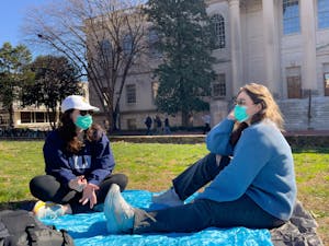 UNC-CH sophomores Sydney Martin and Megan O'Connor wear masks and hang out in the quad in front of Wilson Library on Feb. 6, 2023.