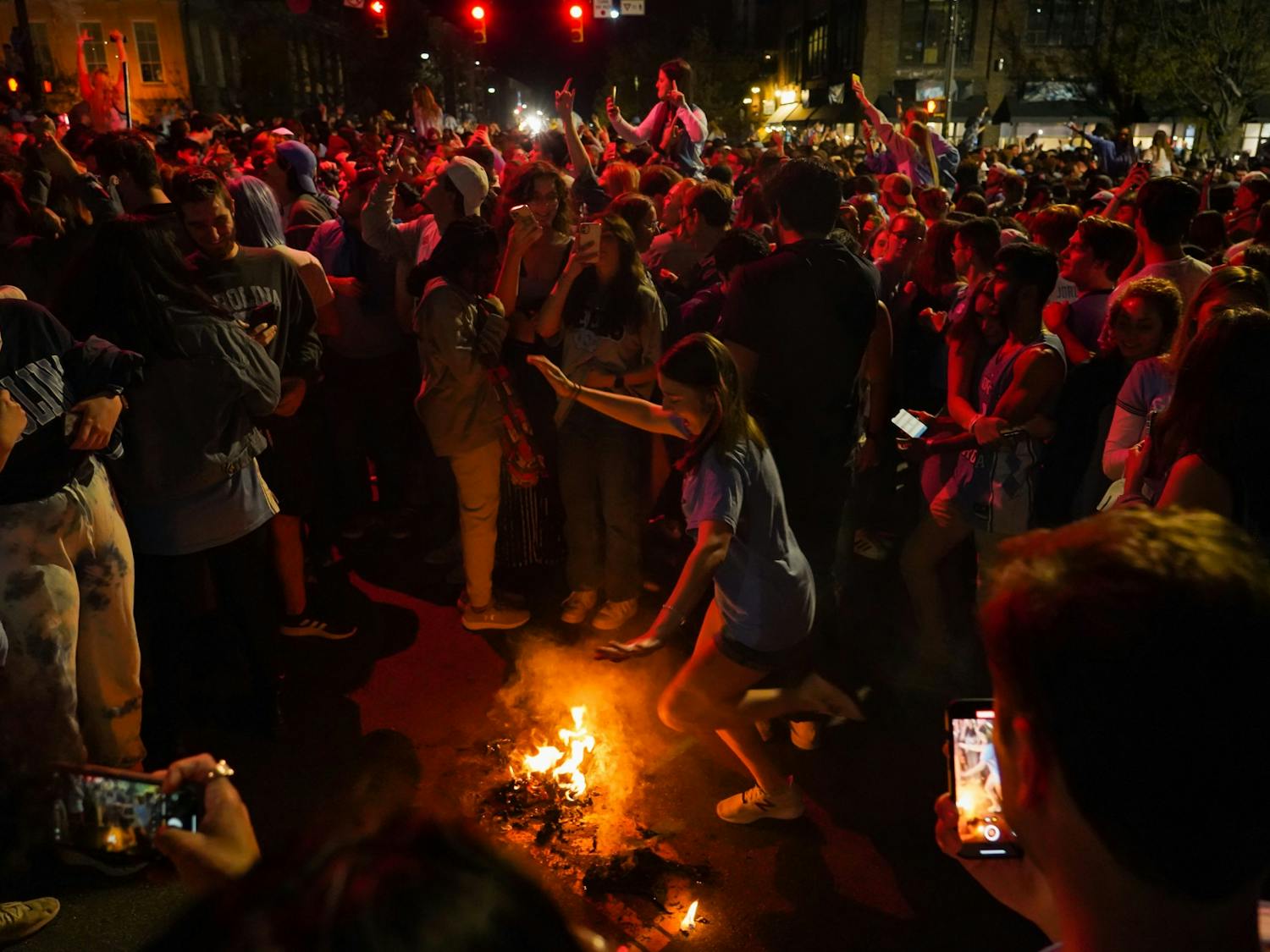 UNC fans jump over a small fire at the intersection of E Franklin and Columbia St. during celebrations after UNC's defeat of Duke in their FInal Four matchup on April 3, 2022. UNC beat Duke 81-77. Photo courtesy of Morgan Pirozzi 