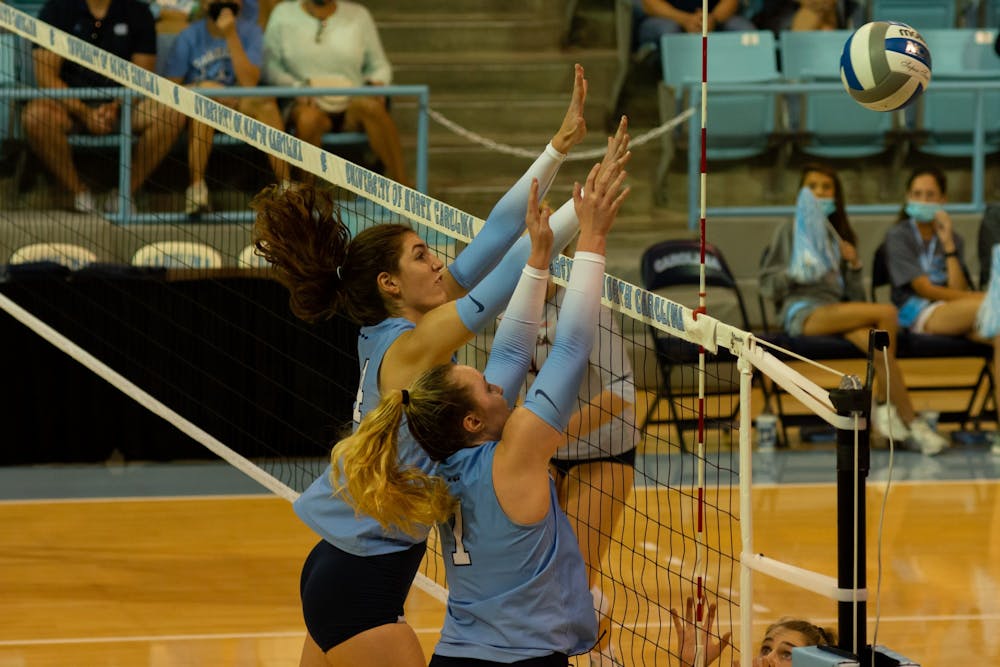 UNC senior middle hitter Amanda Phegley (7) and sophomore middle hitter Kaya Merkler (14) block a hit during a home volleyball game against the University of Virginia on Sept. 26 in Carmichael Arena. 