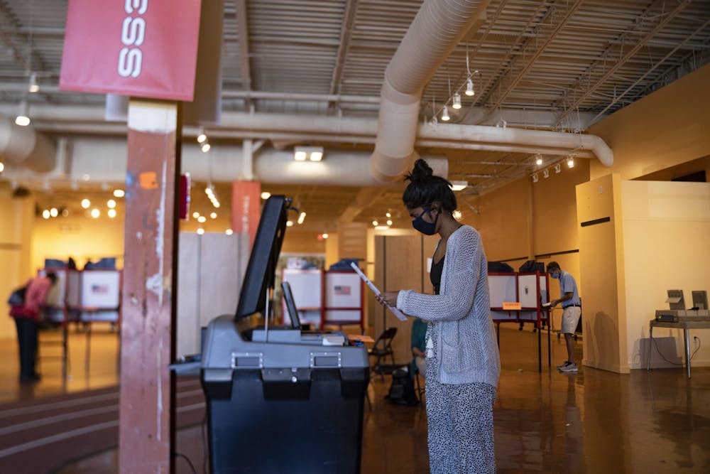 Nisha Iyer turns in her ballot at the early voting site at University Place on Tuesday, Oct. 20, 2020.