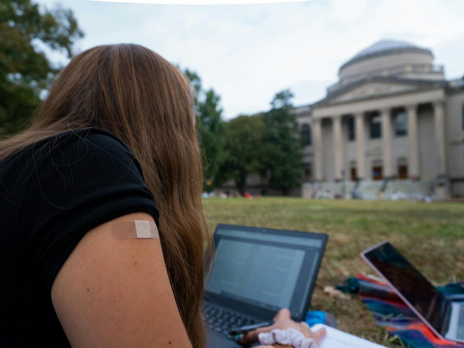 DTH Photo Illustration. A student sits on the quad after receiving a vaccine.