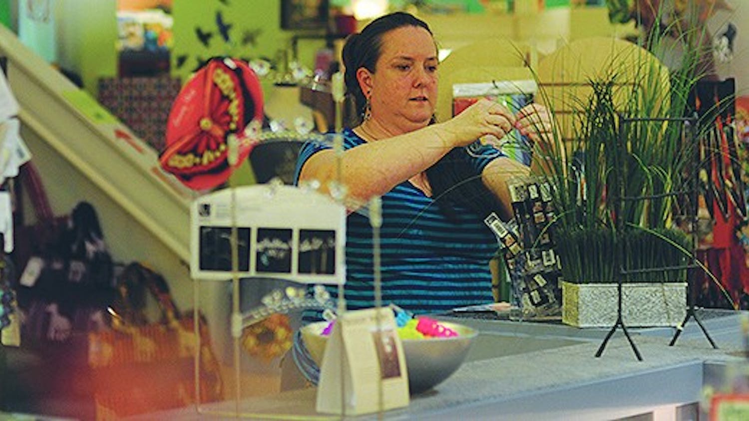 Kara Ikenberry, an employee at Cameron's, rearranges some goods after a long day's work.
