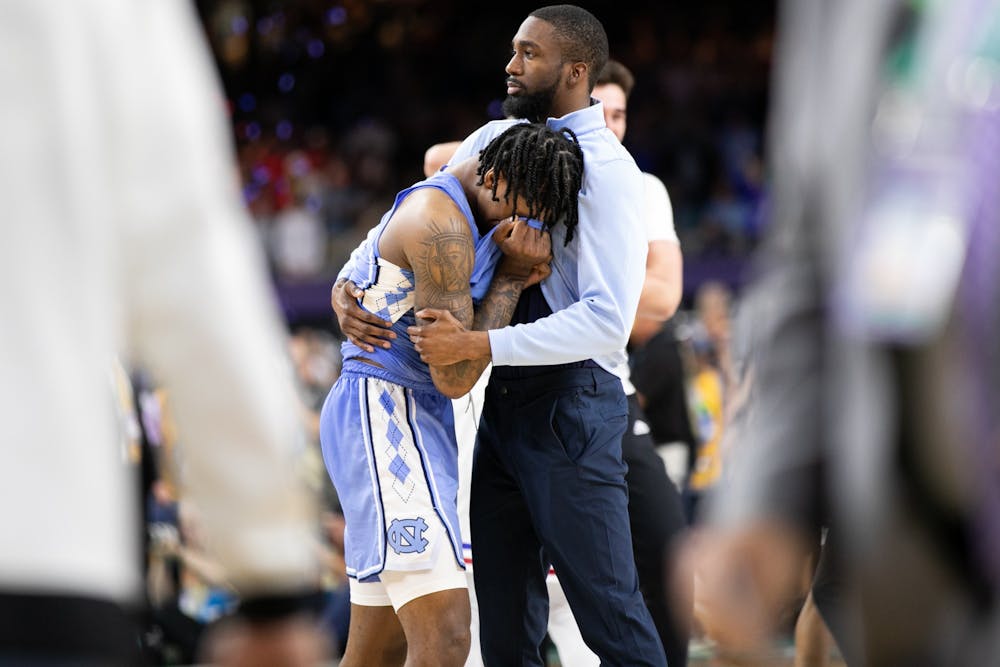 UNC graduate manager Brandon Robinson comforts sophomore guard Caleb Love (2) after a national championship loss to Kansas in New Orleans on Monday, April 4, 2022. UNC lost  72-69.
