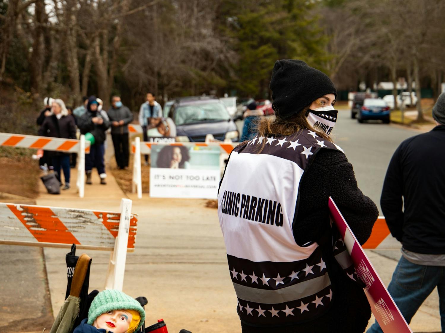 UNC student Reiley Baker stands among other volunteers at A Preferred Women's Health Center of Charlotte, only a few yards from the group of evangelical, anti-abortion activists who protest daily outside the clinic. 