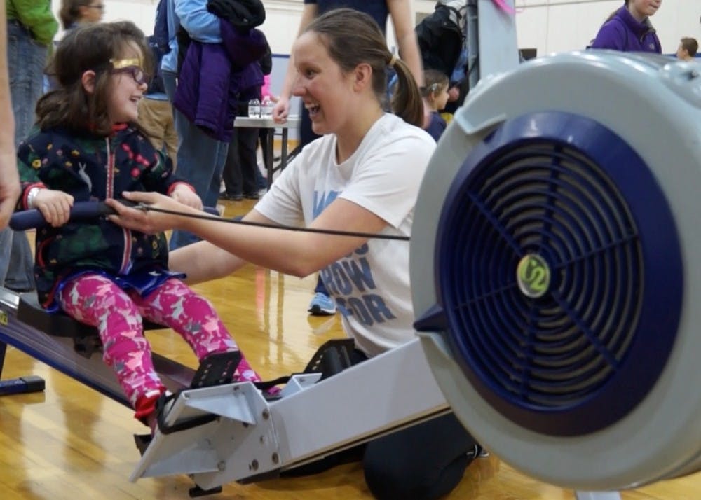 <p>Caroline Young, who is on UNC's women's rowing team, teaches a young girl how to row during National Girls and Women in Sports Day hosted at UNC.</p>