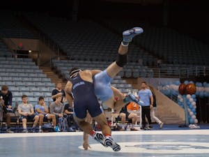 Redshirt senior Ethan Ramos (in Navy) takes down sophomore teammate Devin Kane during UNC's wrestle-offs on Friday night in Carmichael Arena. &nbsp;