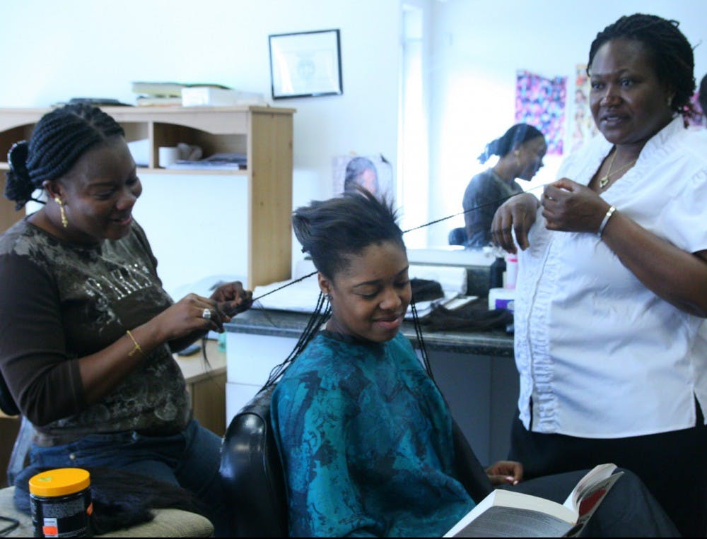 Maguette Mbaye, left, and Stephanie Soulama, right, braid a weave into sophomore Maya Jumper’s hair. DTH/Erica O’Brien