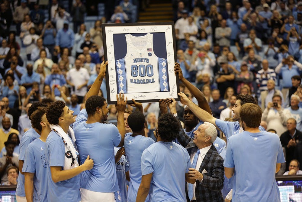 Head coach Roy Williams holds up a framed jersey honoring his 800th win with the men's basketball team after the game against Syracuse.&nbsp;