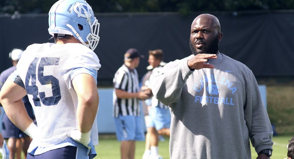 Mikey Bart (45) a, junior defensive end, speaks to Tray Scott after running drills Aug. 20 at Hooker Fields. Tray Scott, who joined the coaching staff this year, is the youngest coach for UNC football.