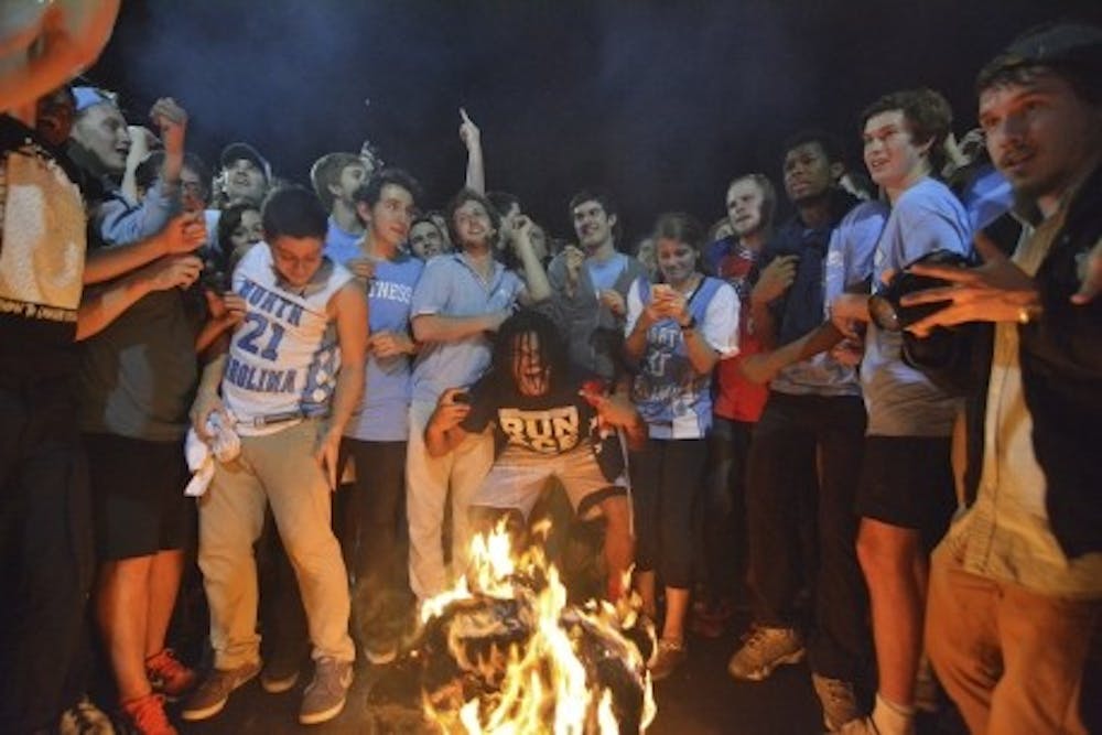<p>Excited fans jump over a bonfire on Franklin Street after North Carolina beats Duke in men’s basketball.</p>