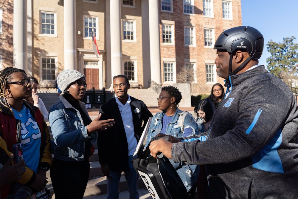 <p>(From left) UNC students De'Ivyion Drew, Tamia Sanders, Chris Suggs and Keoana Nettles lay out several grievances they have with UNC police to Chief Perry. These criticisms referenced &nbsp;officer turnout at public meetings, Chief Perry's demeanor and appearance at the protest, and police behavior at protests. UNC's Black Student Movement, Black Congress and student and local activists convened in McCorkle place before marching to South Building on Thursday, Dec. 5, 2019 at 1 p.m. The activists named the event "Silent Sam is Not "Resolved"" and protested the University giving a $2.5 million trust fund to the Sons of Confederate Veterans and Silent Sam in a deal which removed Silent Sam from campus.&nbsp;</p>