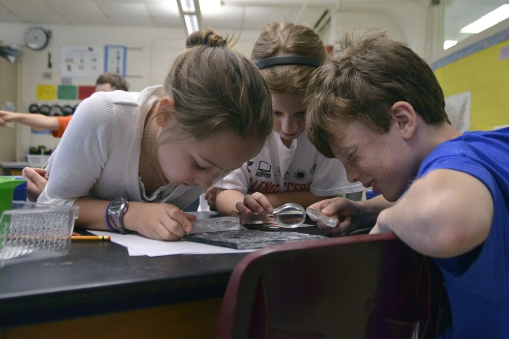 Students at Carrboro Elementary School attend classes in English for half of the day and a foreign language for the second half of the day as part of a dual language immersion program. These programs result in higher EOG test scores. Nathan Ludington (10), Lucy Mills (9), and Maddie Hamilton (10) study fossils during the English portion of their day.