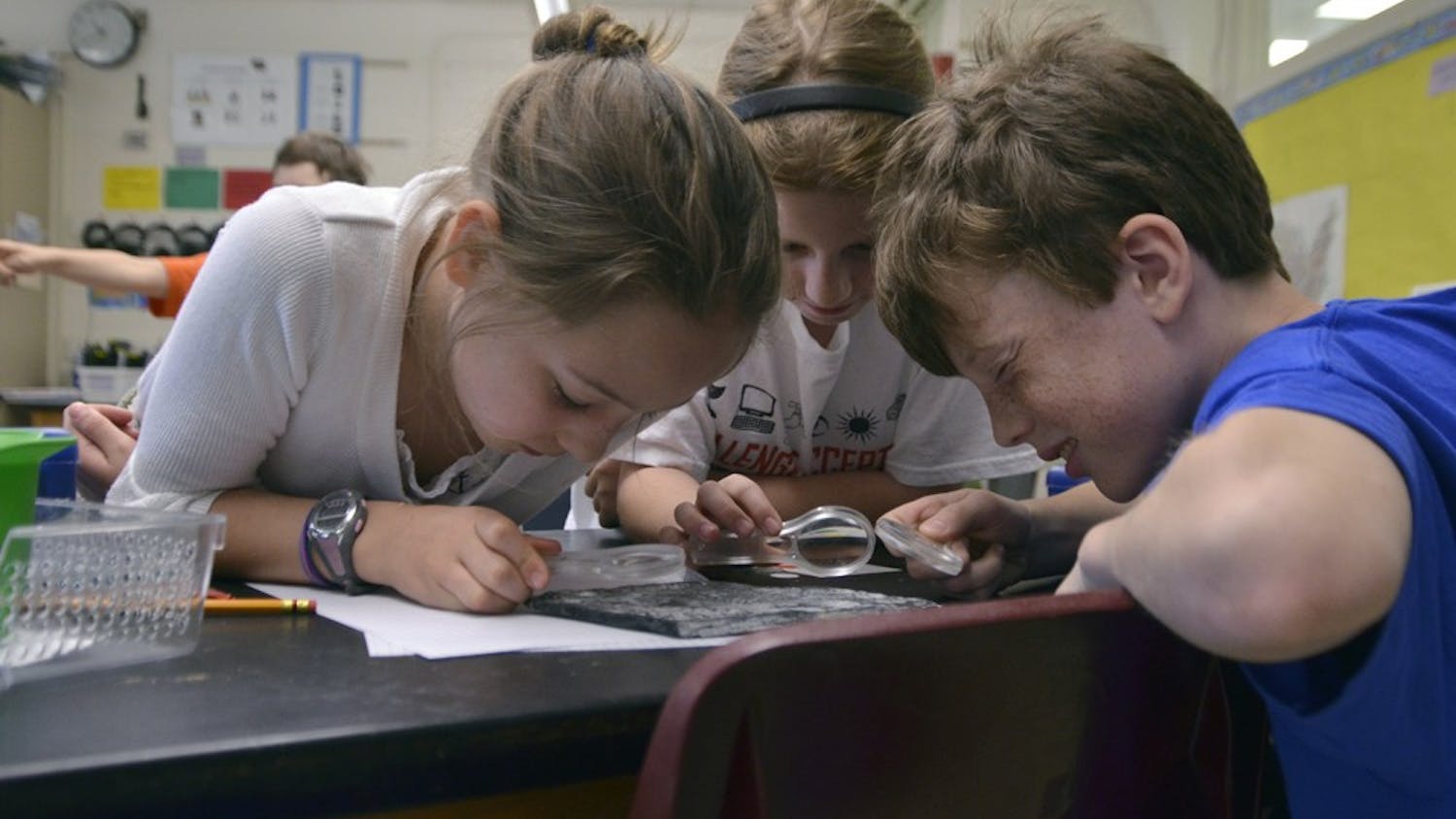 Students at Carrboro Elementary School attend classes in English for half of the day and a foreign language for the second half of the day as part of a dual language immersion program. These programs result in higher EOG test scores. Nathan Ludington (10), Lucy Mills (9), and Maddie Hamilton (10) study fossils during the English portion of their day.