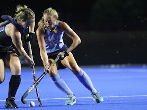 First-year midfielder Grace Poutebaum (16) clashes sticks as she goes for the ball. UNC beat Duke 4-1 away on Saturday, Aug. 20, 2022.