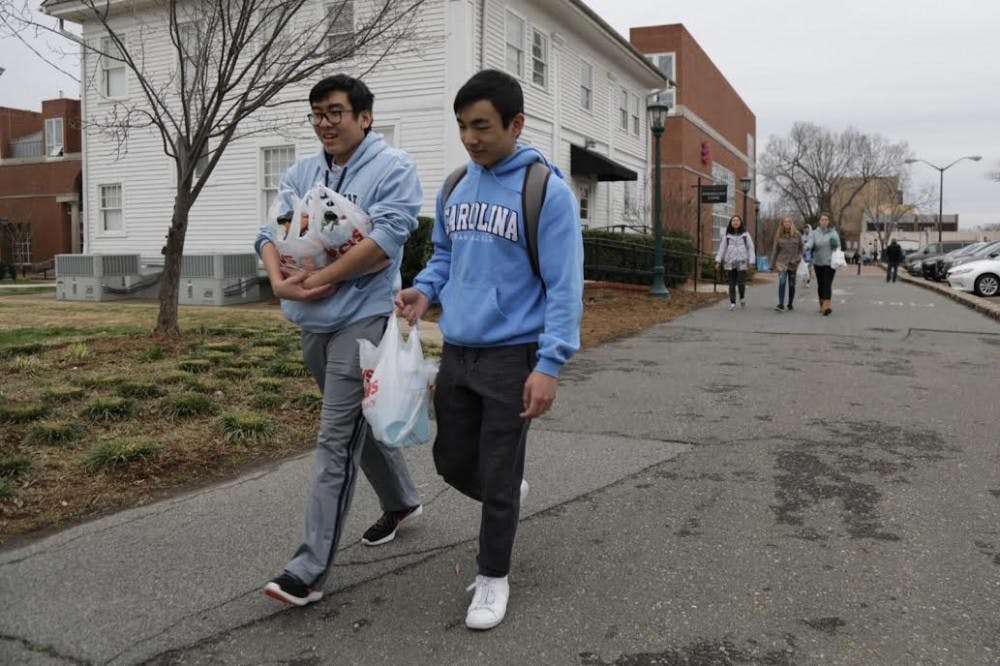 <p>UNC students Dean Tran and Harvey Liu walk back to campus holding bags of Powerade after not finding water on Franklin Street.&nbsp;</p>