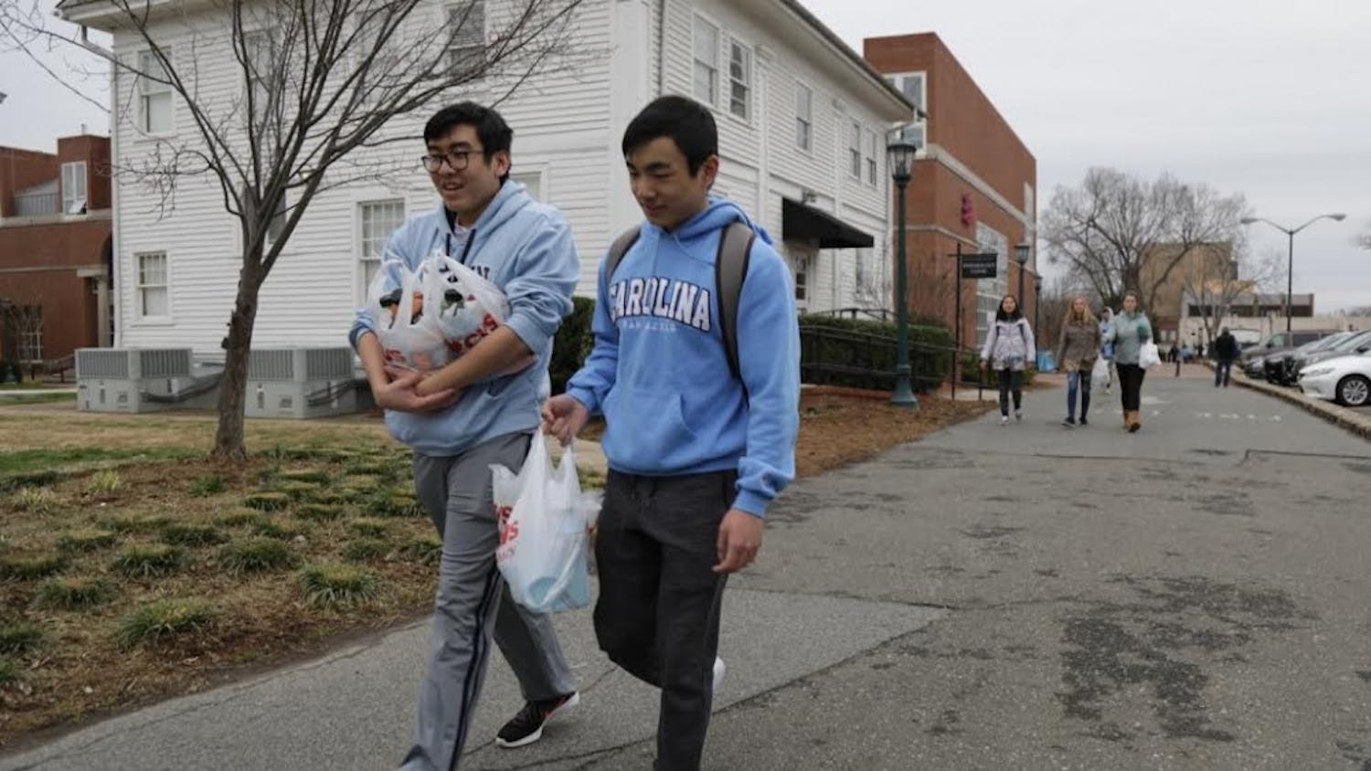 UNC students Dean Tran and Harvey Liu walk back to campus holding bags of Powerade after not finding water on Franklin Street.&nbsp;