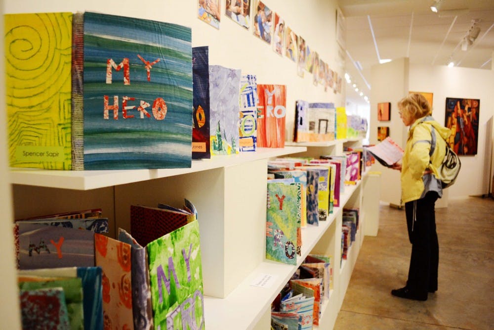 FRANK gallery exhibit, "Meet Our Heros" displays the work of Durham Academy 6th grade students. The students created pop-up books that tell the story of their heroes. Ridna Frasbergen looks at one of the books created by her grandson's classmate. 