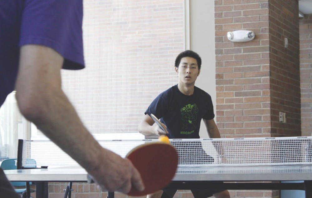 Senior Calvin Young plays pingpong Saturday against 81-year-old Walter Shur. DTH/Alyssa Champion