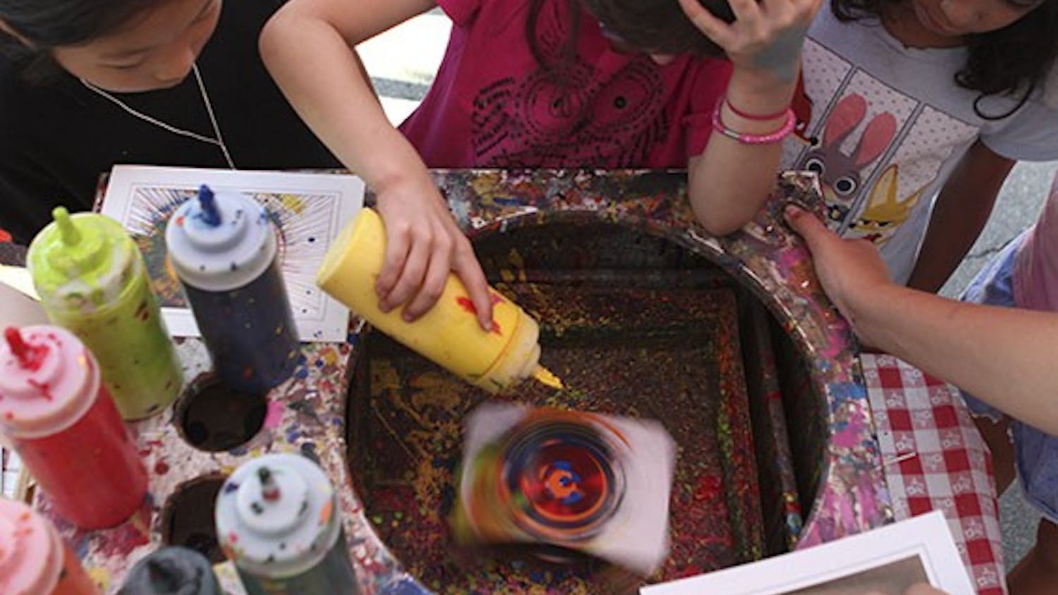 Olivia Valdes creates a work of spin art at the Carrboro ArtsCenter booth at Festifall on West Franklin Street on Sunday afternoon.