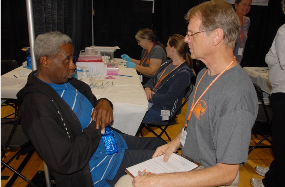 Charles Gear (left) attends Project Homeless Connect each year at the Hargraves Center in the Northside neighborhood.  Here, he gets his cholesterol screened by volunteer physician Steve Burnham.  The screening was sponsored by the Orange County Health Department.