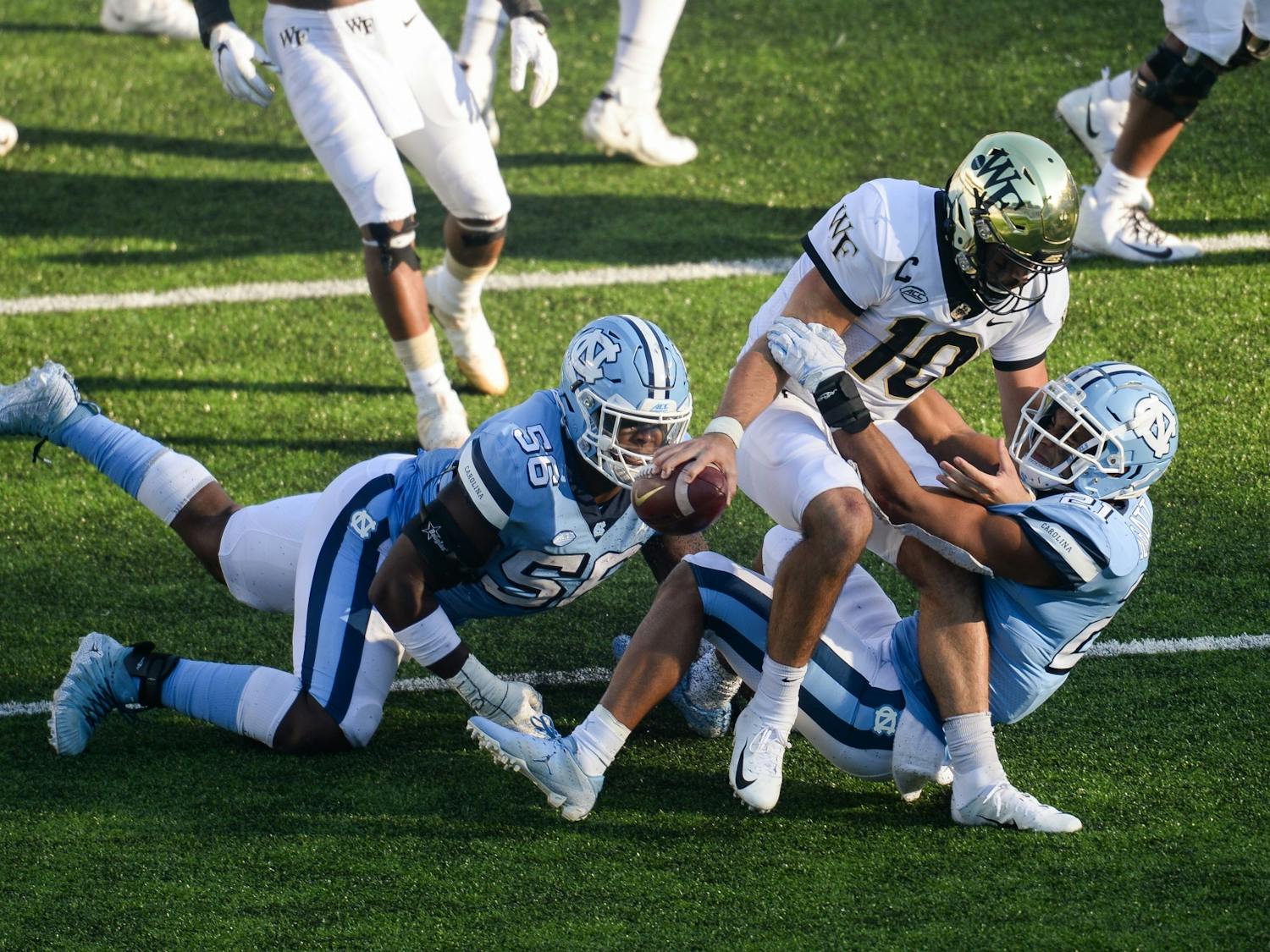 Wake Forest's redshirt sophomore quarterback Sam Hartman (10) is sacked by UNC's graduate linebacker Chazz Surratt (21) and sophomore defensive lineman Tomari Fox (56) during a game in Kenan Memorial Stadium on Saturday, Nov. 14, 2020. UNC beat Wake Forest 59-53.